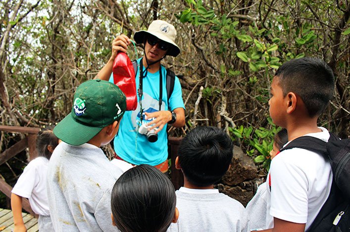 Students from Stella Maris School learn about plastic pollution after finding a plastic bottle full of barnacles in the mangroves of Isabela Island